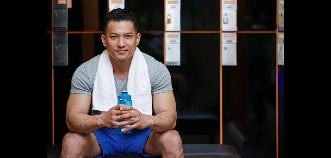 Pria dengan handuk di gym usai latihan, gambaran artikel tentang fat burner terbaik untuk mendukung pembakar lemak dan performa olahraga