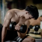 Pria angkat beban saat latihan gym untuk menggambarkan pentingnya kebutuhan protein harian gym dalam membangun otot